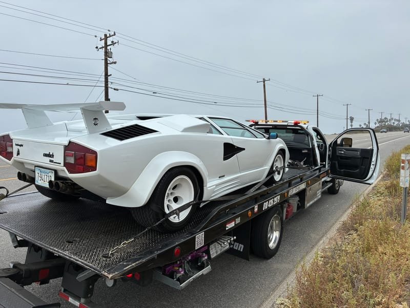 A white Lamborghini Countach secured on a Flawless Towing flatbed on the Pacific Coast Highway