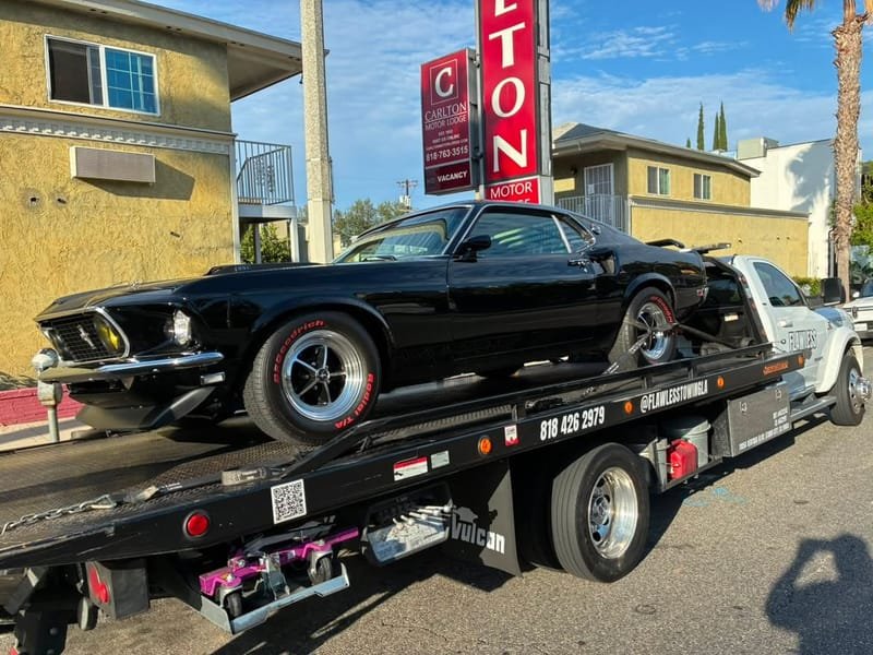 A black 1969 Ford Mustang Mach 1 loaded on a flatbed in Studio City