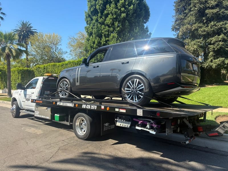 A Range Rover on the Flawless Towing flatbed on a residential street lined with palm trees