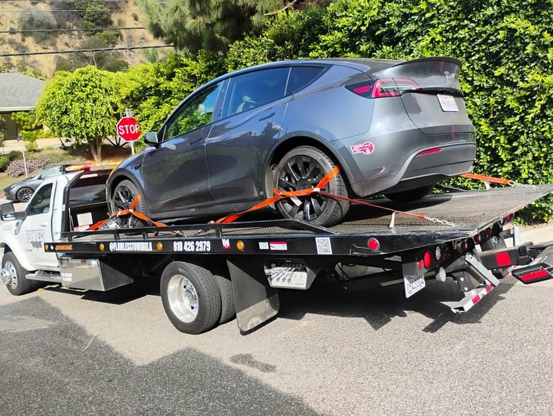 A grey Tesla Model Y strapped to a Flawless Towing flatbed